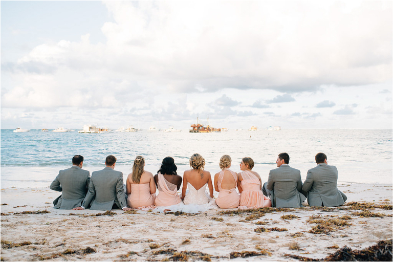 wedding party sitting in the sand